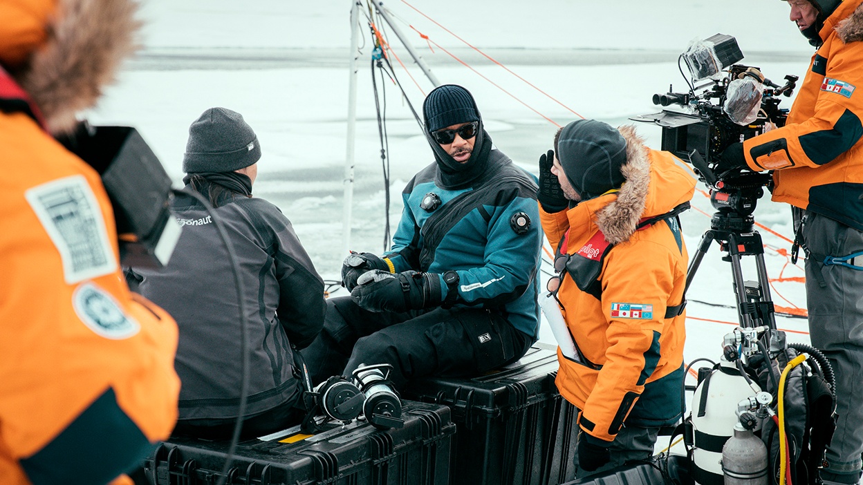 Will Smith prepares to dive under the ice with Dr. Allison Fong to collect samples in the waters of the North Pole. Image courtesy of National Geographic/Freddie Claire.